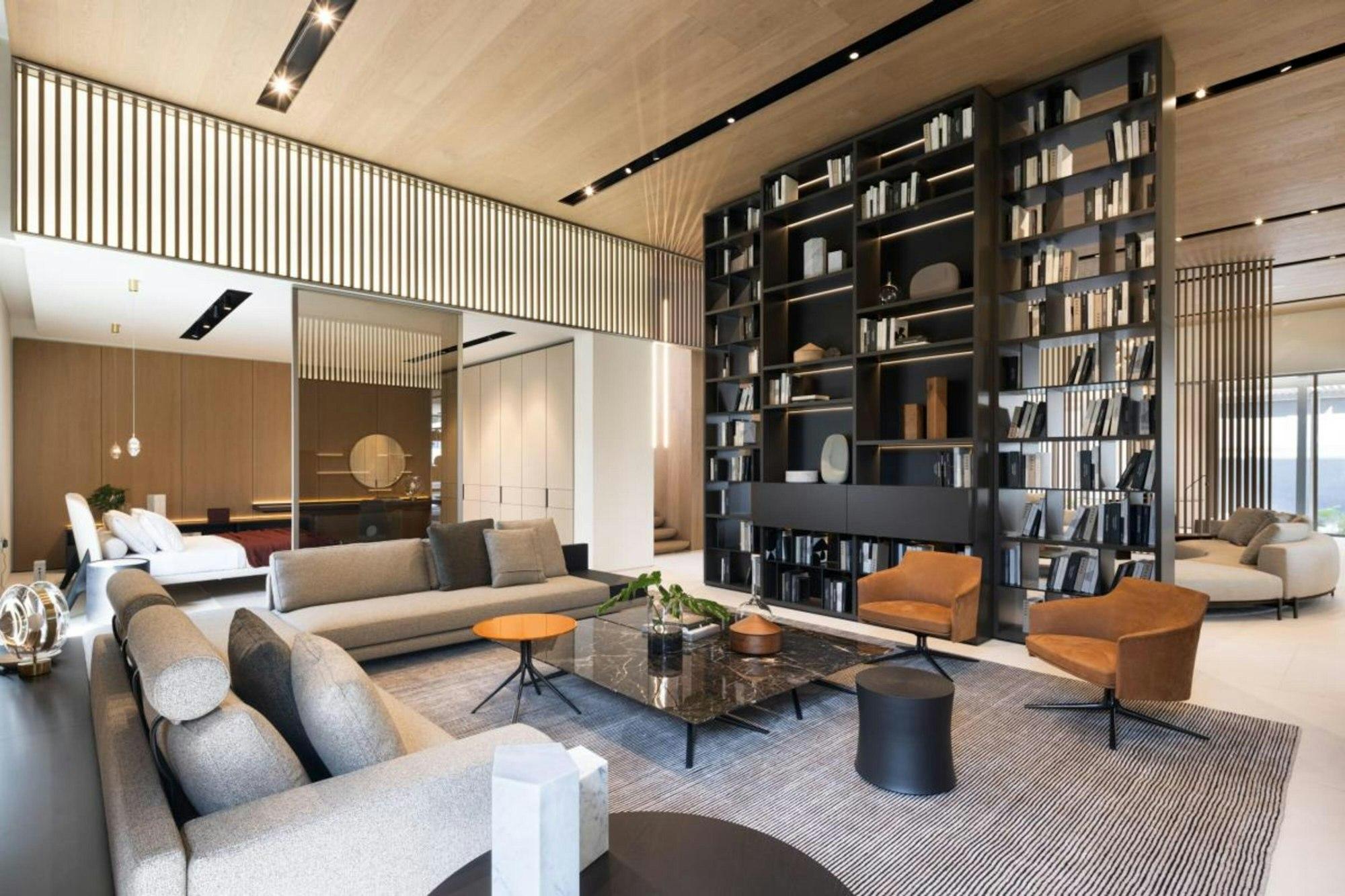 Double-height clubhouse lounge with a library wall and soft seating